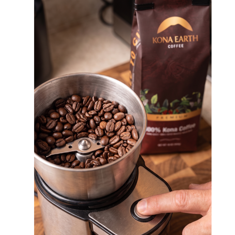 Kona beans in a grinder with Kona Earth coffee bag sitting beside