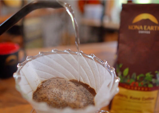 a pour over in process with a bag of Kona Earth peaberry sitting in the background
