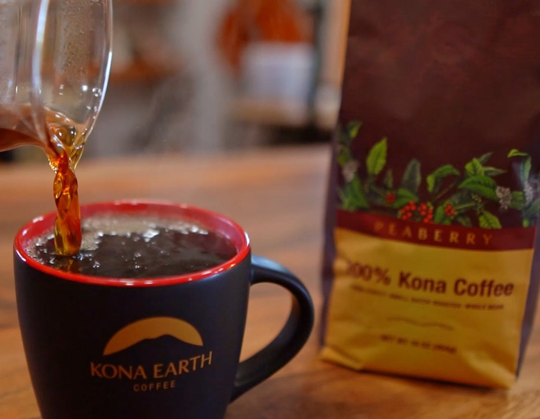 Kona coffee is being poured into a black cup. a bag of Kona Peaberry sits just behind and slightly out of focus.